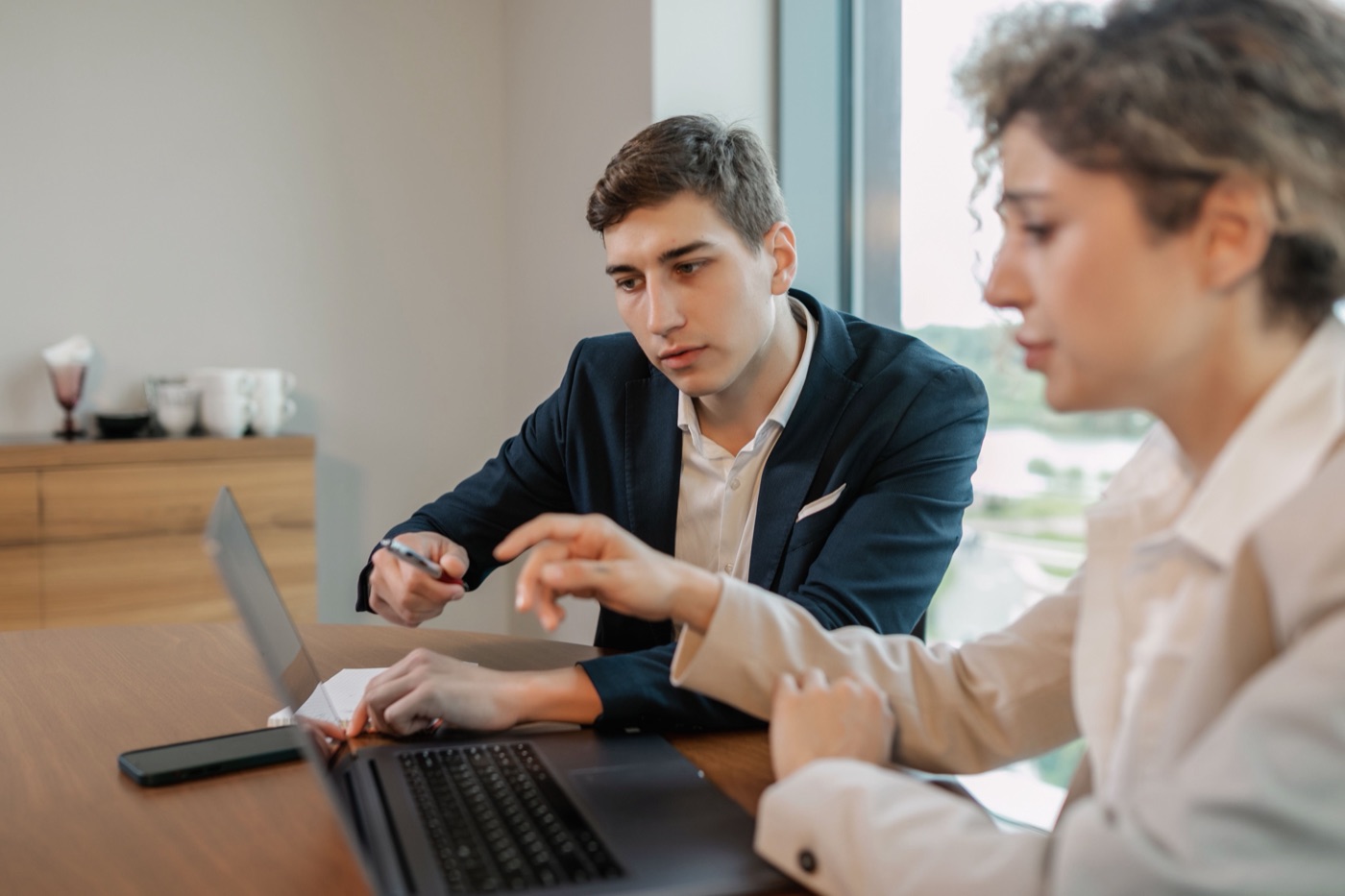 A consultant walking a client through project status on a laptop